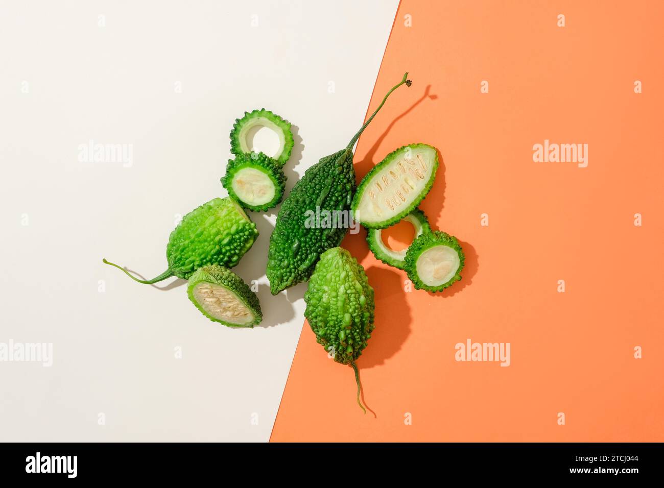 El melón amargo fresco se destaca sobre un fondo rojo y blanco. Uno de