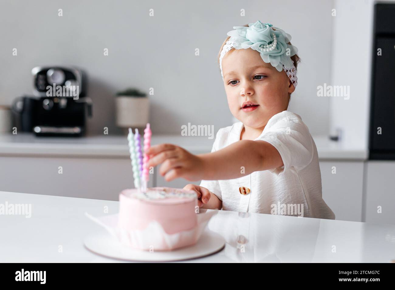 feliz cumpleaños niña de 2 años con vestido rosa. pastel blanco con velas y  rosas. Decoración de cumpleaños con globos de color blanco y rosa y c  Fotografía de stock - Alamy