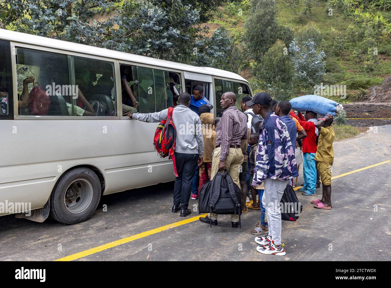 Pasajeros que cambian de autobús después de un bloqueo de carretera causado por deslizamientos de lodo en la provincia occidental de Ruanda Foto de stock