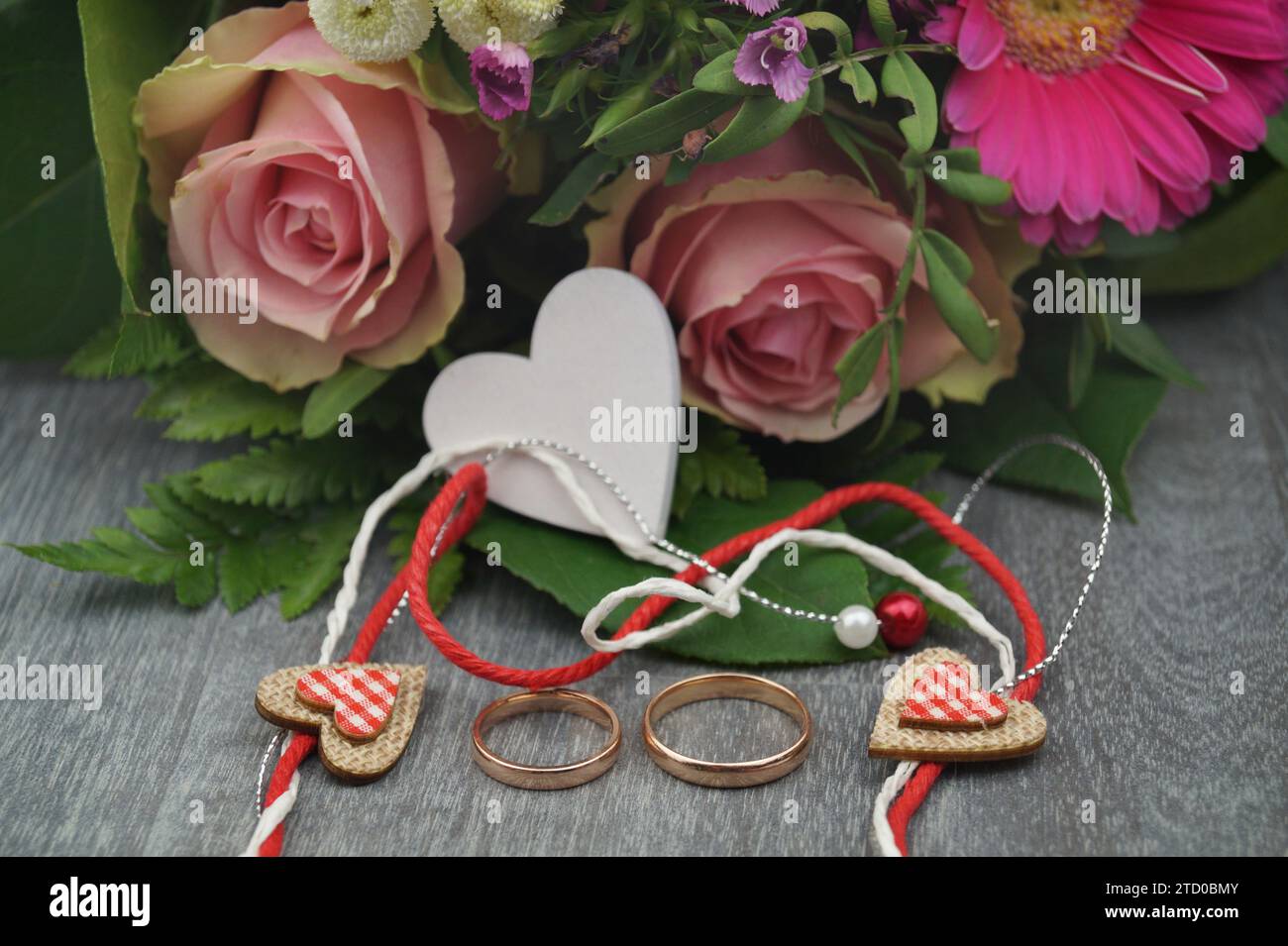 ramo fresco de flores con corazón de madera blanco, decoración de corazón pequeño y anillos de boda Foto de stock