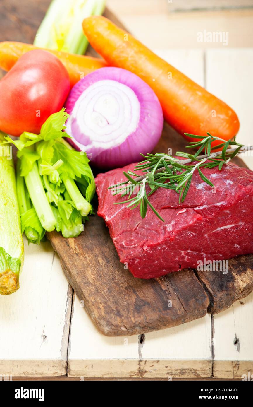 Carne fresca cruda cortada lista para cocinar con verduras y hierbas, fotografía de alimentos Foto de stock