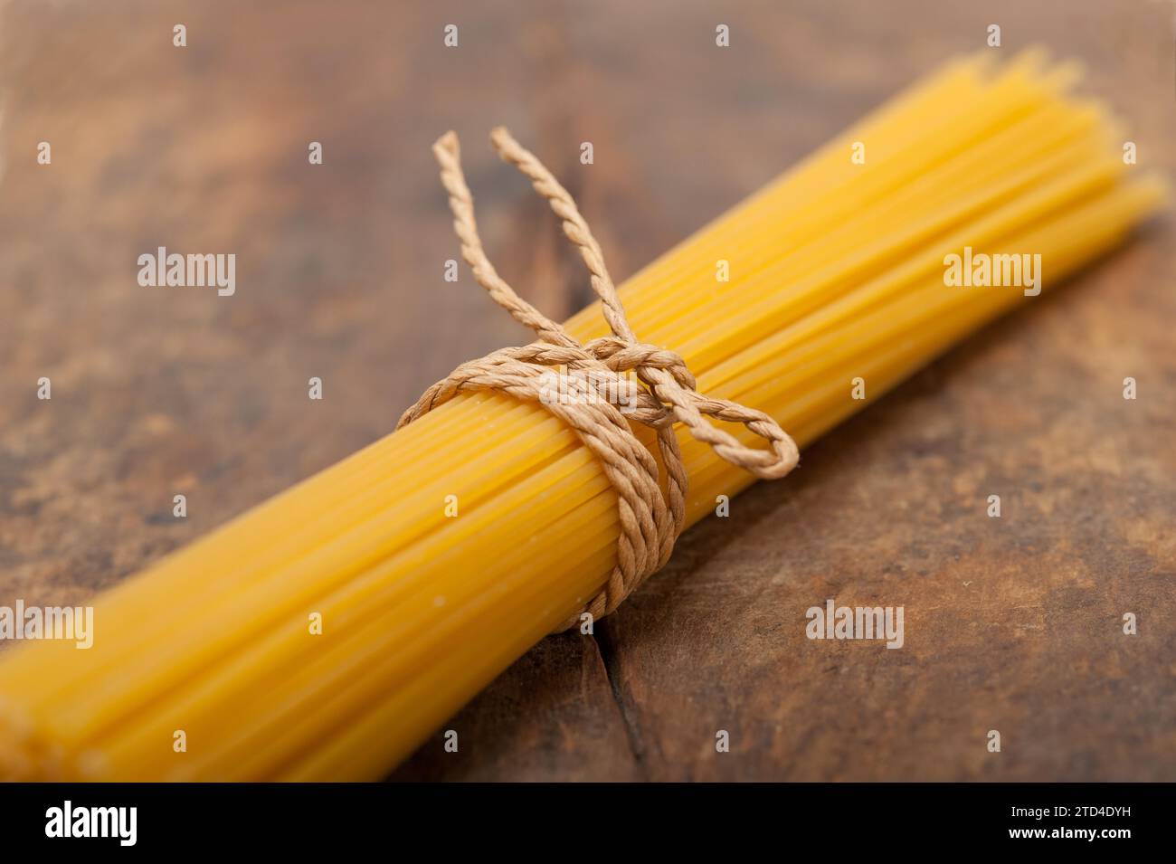Las pastas italianas espaguetis atados con una cuerda en una tabla rústica Foto de stock