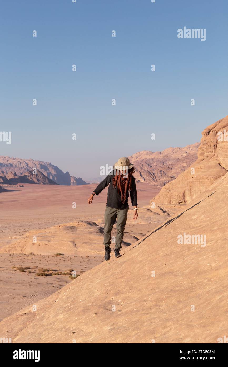 Hombre de pelo rizado con sombrero, senderismo en el desierto de Wadi Rum, Jordania Foto de stock