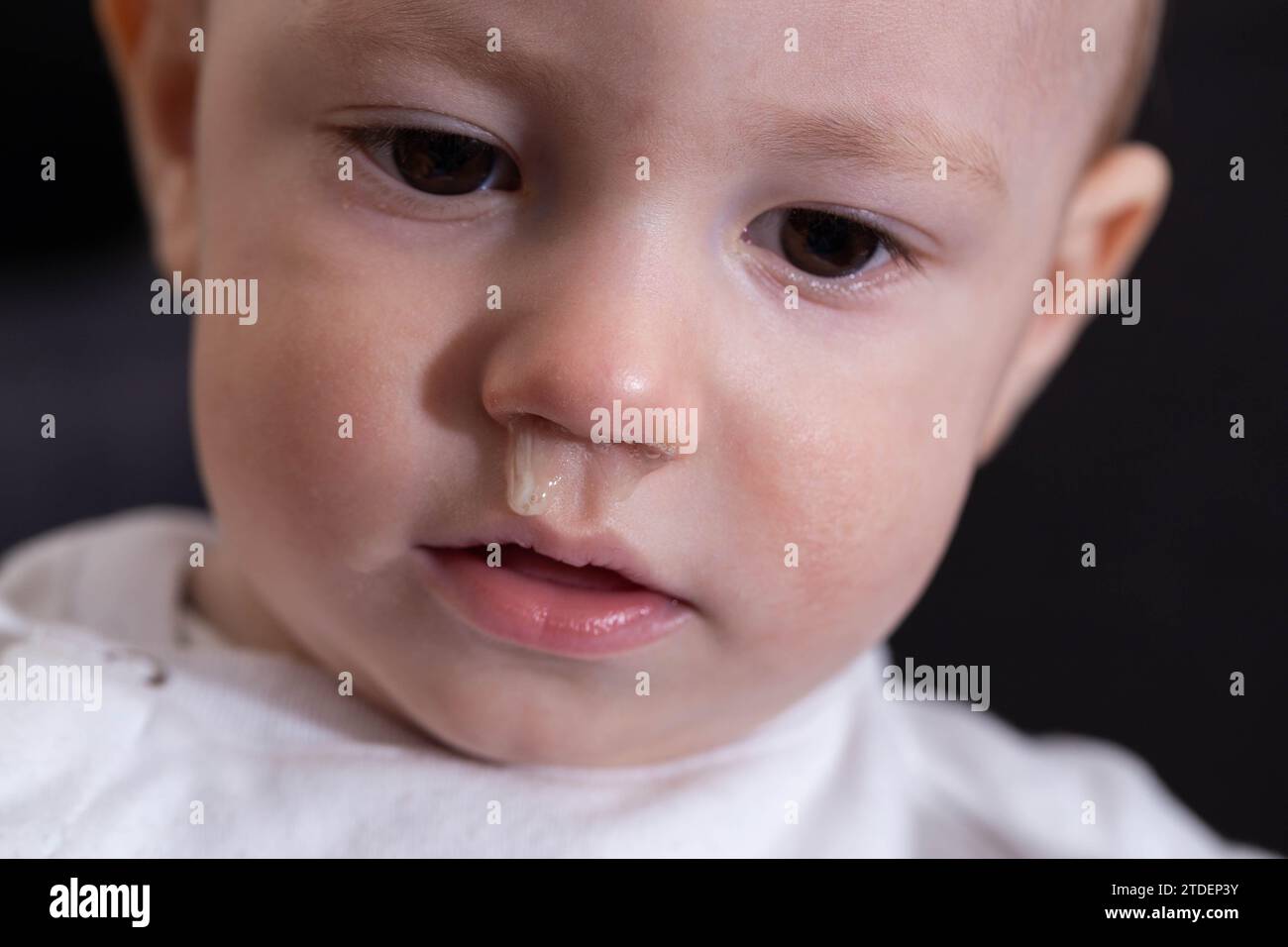 Cara de un bebé sonriente con el moño de su nariz. Secreción nasal y