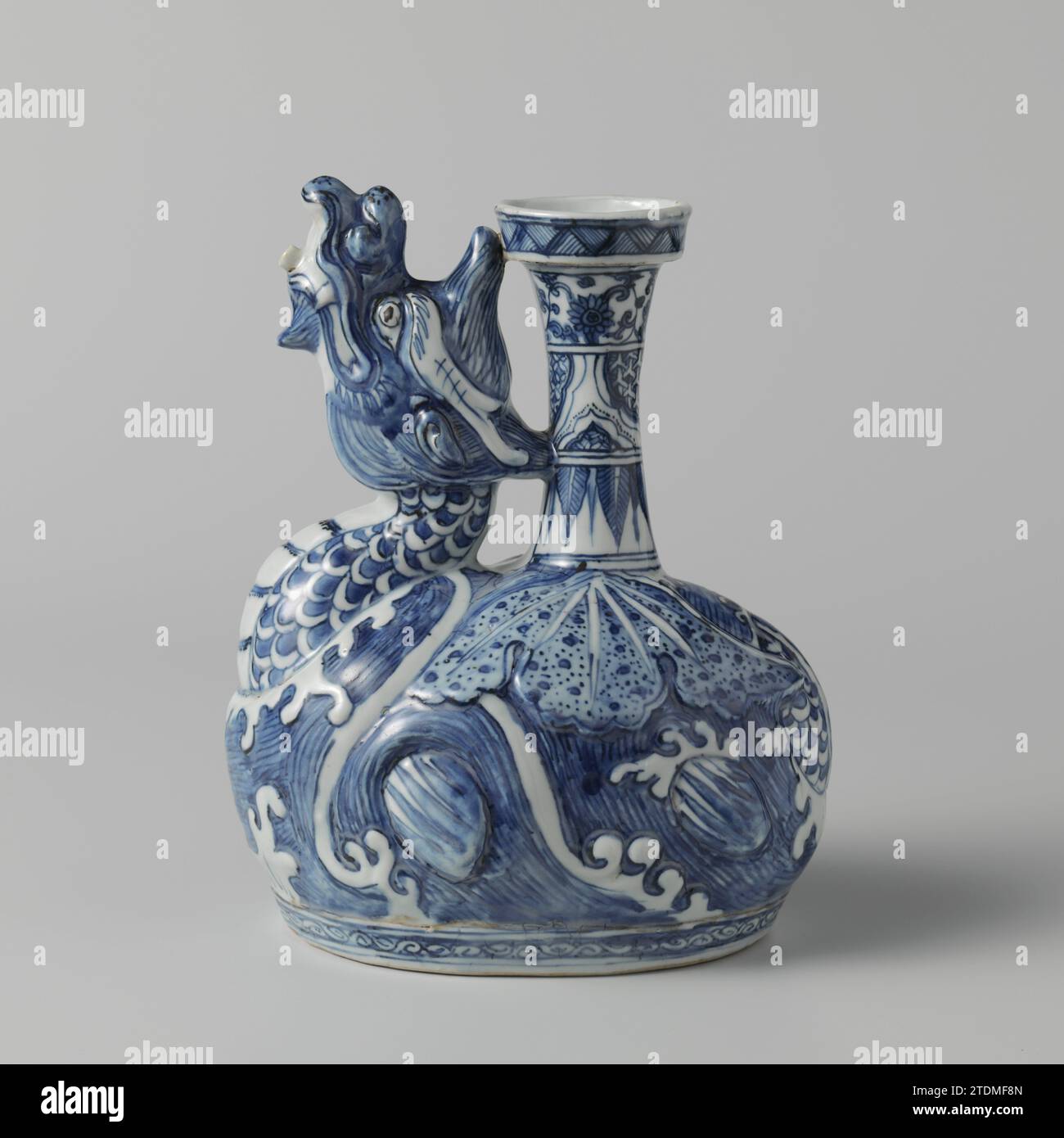 Kendi en forma de dragón, anónimo, c. 1575 - c. 1599 Kendi van Porcelain, pintado en azul undermglaze. El Kendi es modelado en la forma de un dragón que se levanta de las olas con alas extendidas y cubierto con una hoja de loto; el cuello y la cabeza del dragón forman el pico; el cuello se divide en tres neumáticos con colgantes, motivos de hojas puntiagudas, compartimentos festoneados con servetwork o vides de flores; el borde elevado con chanclas; alrededor del pie un neumático con rizo. Porcelana Ming en azul y blanco. Porcelana de China. esmalte. Pintura de cobalto (mineral) / vitrificación Kendi van Porcelana, pintado en unde Foto de stock