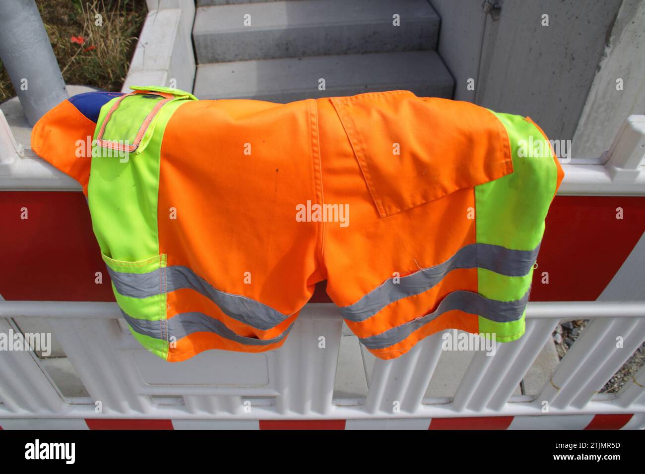 Pantalones cortos de trabajo cuelgan sobre una barrera de advertencia para secar Foto de stock