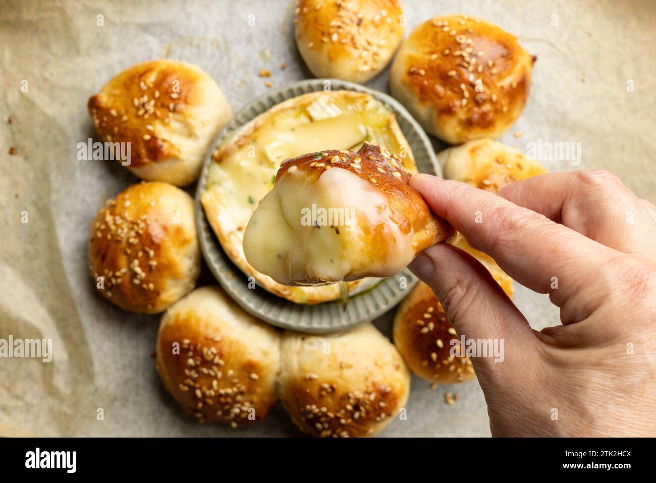 primer plano de panecillos recién horneados con queso brie derretido en mano humana, vista superior Foto de stock