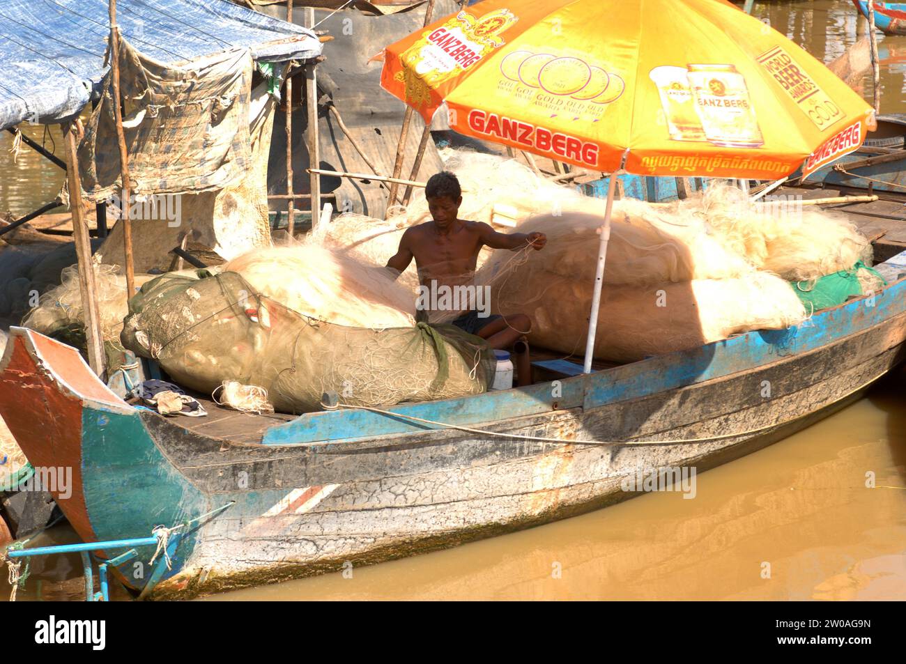 Hombre reparando sus redes de pesca, pueblo flotante Kampong Phluk en Tonle Sap Lake, Camboya, Asia. Foto de stock