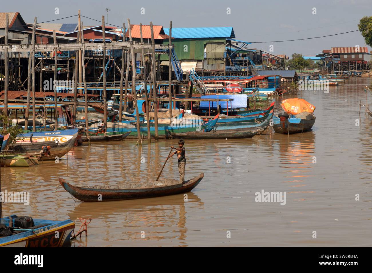 Muchacho en el pequeño barco que se mueve a lo largo de las vías fluviales, pueblo flotante Kampong Phluk en el lago Tonle Sap, Camboya, Asia. Foto de stock