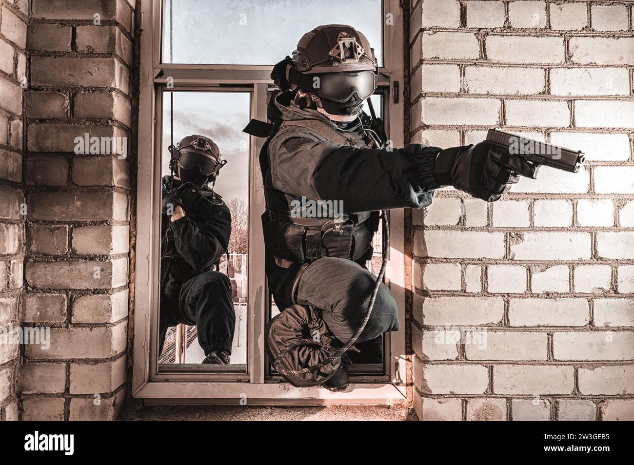 Grupo de combatientes de fuerzas especiales asaltan el edificio a través de la ventana. Sesiones de formación del equipo SWAT. Concepto antiterrorista. Escaladores. Medios mixtos Foto de stock