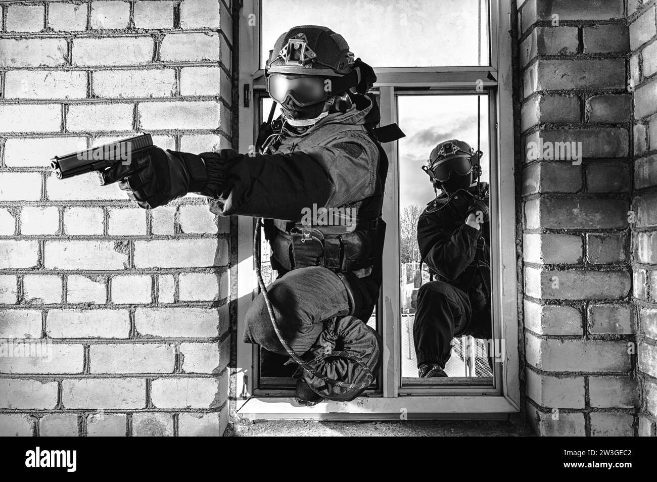 Grupo de combatientes de fuerzas especiales asaltan el edificio a través de la ventana. Sesiones de formación del equipo SWAT. Concepto antiterrorista. Escaladores. Medios mixtos Foto de stock