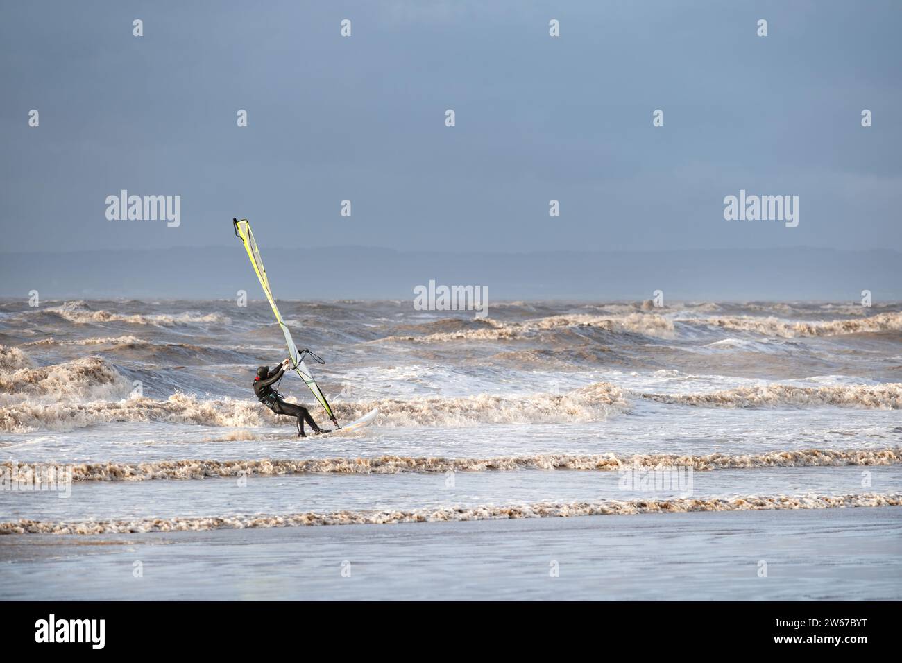 UK Weston super mare: Un surfista de viento lucha contra fuertes vientos y grandes olas mientras viaja a toda velocidad a lo largo del agua cerca de la costa Foto de stock