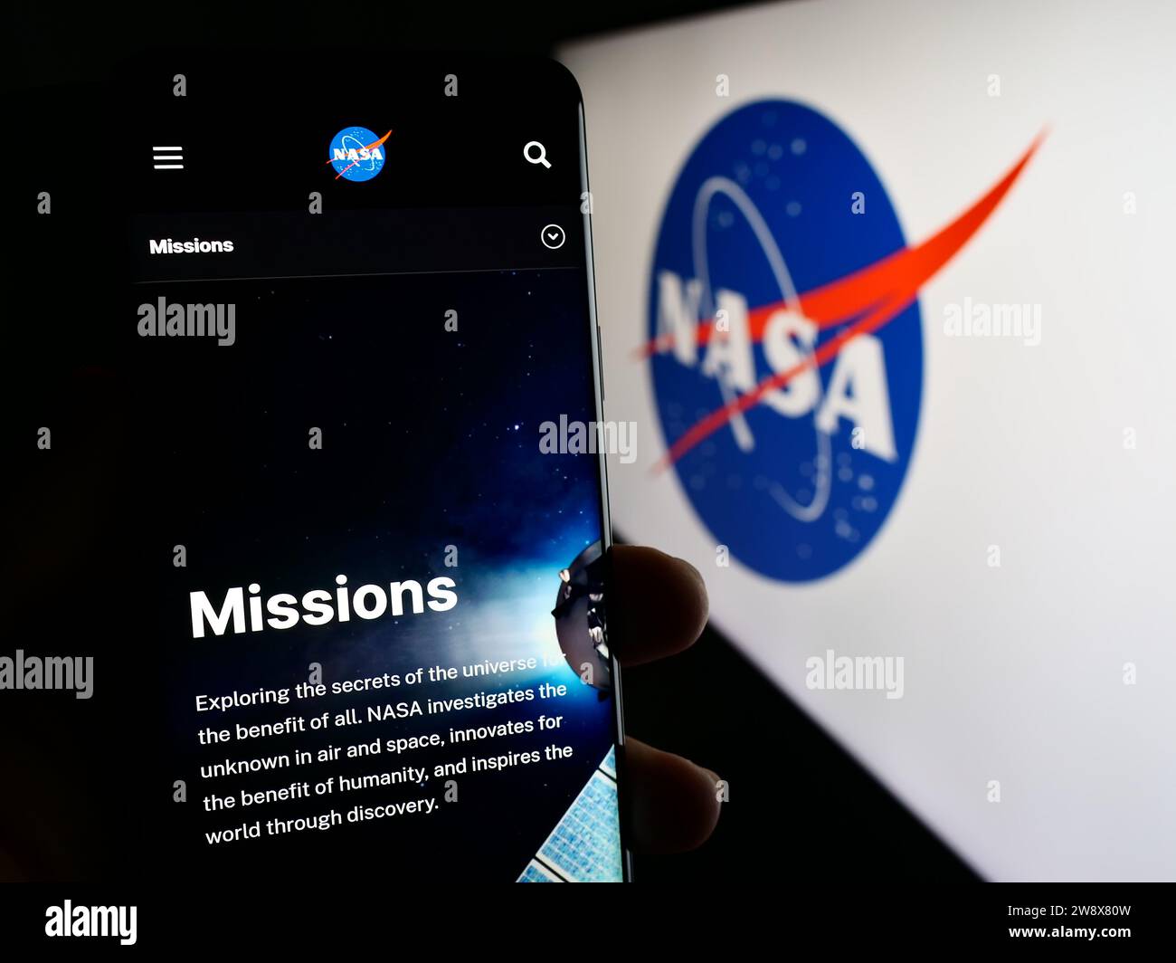 Persona que sostiene el teléfono móvil con la página web de la Administración Nacional de Aeronáutica y del Espacio de los Estados Unidos (NASA) con el logotipo. Enfoque en el centro de la pantalla del teléfono. Foto de stock