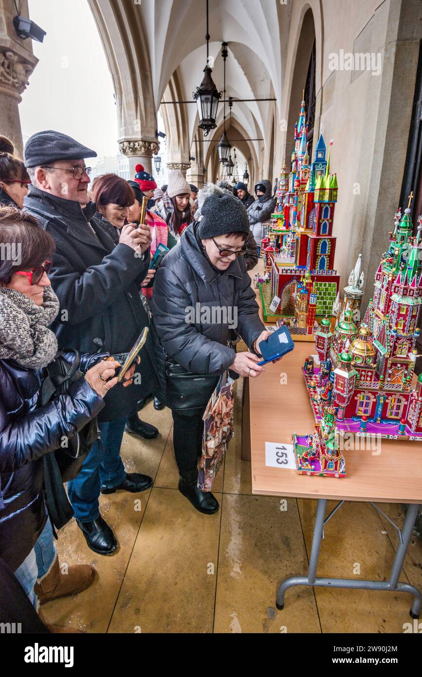 Personas que toman fotos de Szopki (Belén de Navidad) en la apertura del concurso anual en diciembre, evento incluido en la lista del Patrimonio Cultural de la UNESCO, en las salas de juegos de Sukiennice (Salón de telas), Plaza del Mercado Principal, Kraków, Polonia Foto de stock
