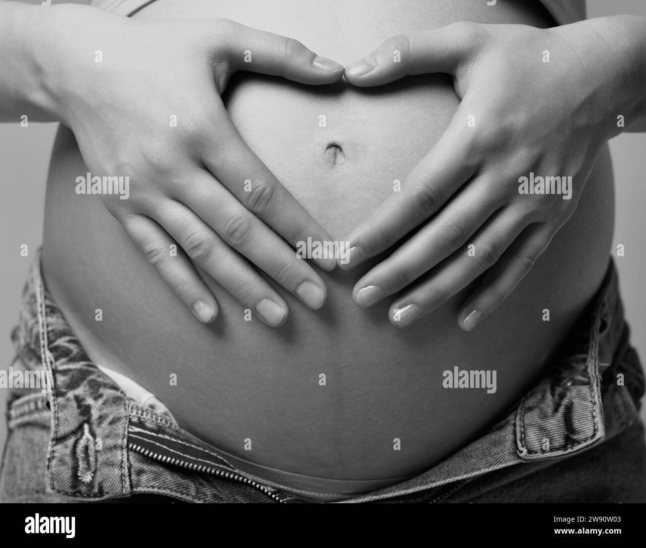Sección intermedia de mujer embarazada sujetando el vientre vistiendo un  Collar Llamador de angel Fotografía de stock - Alamy