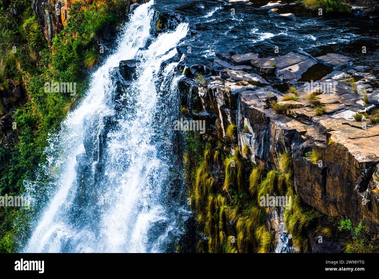 Un paisaje espectacular con una poderosa cascada que cae en cascada por una ladera escarpada de la montaña, vista desde un ángulo elevado Foto de stock
