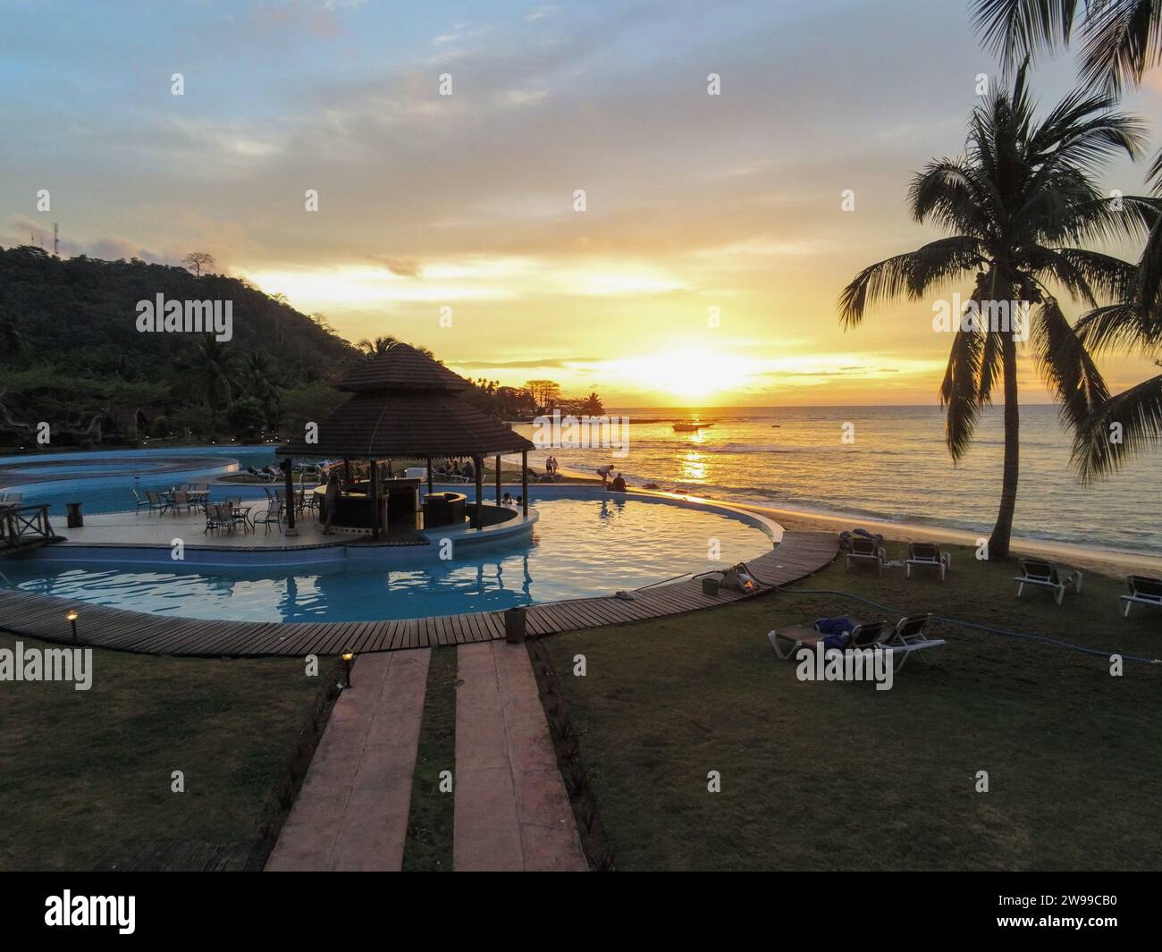 Vista increíble desde la piscina en un complejo en Ilheu das Rolas, Santo tomé con puesta de sol reflejándose en el mar, África Foto de stock
