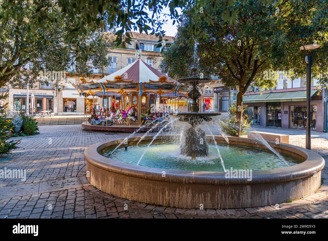 Fuente y carrusel en una plaza, en Brive la Gaillarde, en Corrèze, Nouvelle-Aquitaine, Francia Foto de stock