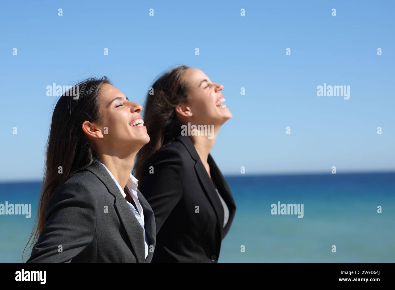 Perfil de dos ejecutivos felices relajándose respirando aire fresco en la playa Foto de stock