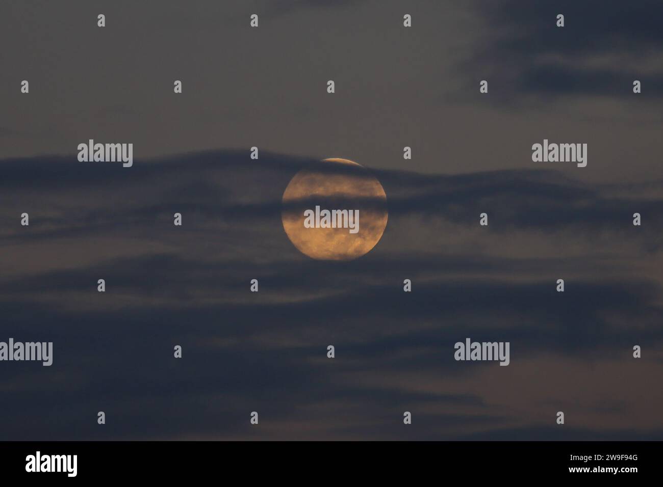 Bogotá, Colombia. 27 de diciembre de 2023. Vista general de la última luna llena de 2023, también conocida como la Luna Fría, se ve a través de las nubes al amanecer sobre la ciudad de Bogotá. El 27 de diciembre de 2023 en Bogotá, Colombia. (Imagen de crédito: © José Isaac Bula Urrutia/eyepix vía ZUMA Press Wire) ¡SOLO USO EDITORIAL! No para USO comercial! Foto de stock