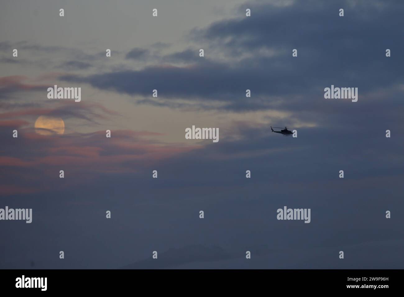 Bogotá, Colombia. 27 de diciembre de 2023. Vista general de la última luna llena de 2023, también conocida como la Luna Fría, se ve a través de las nubes al amanecer sobre la ciudad de Bogotá. El 27 de diciembre de 2023 en Bogotá, Colombia. (Imagen de crédito: © José Isaac Bula Urrutia/eyepix vía ZUMA Press Wire) ¡SOLO USO EDITORIAL! No para USO comercial! Foto de stock