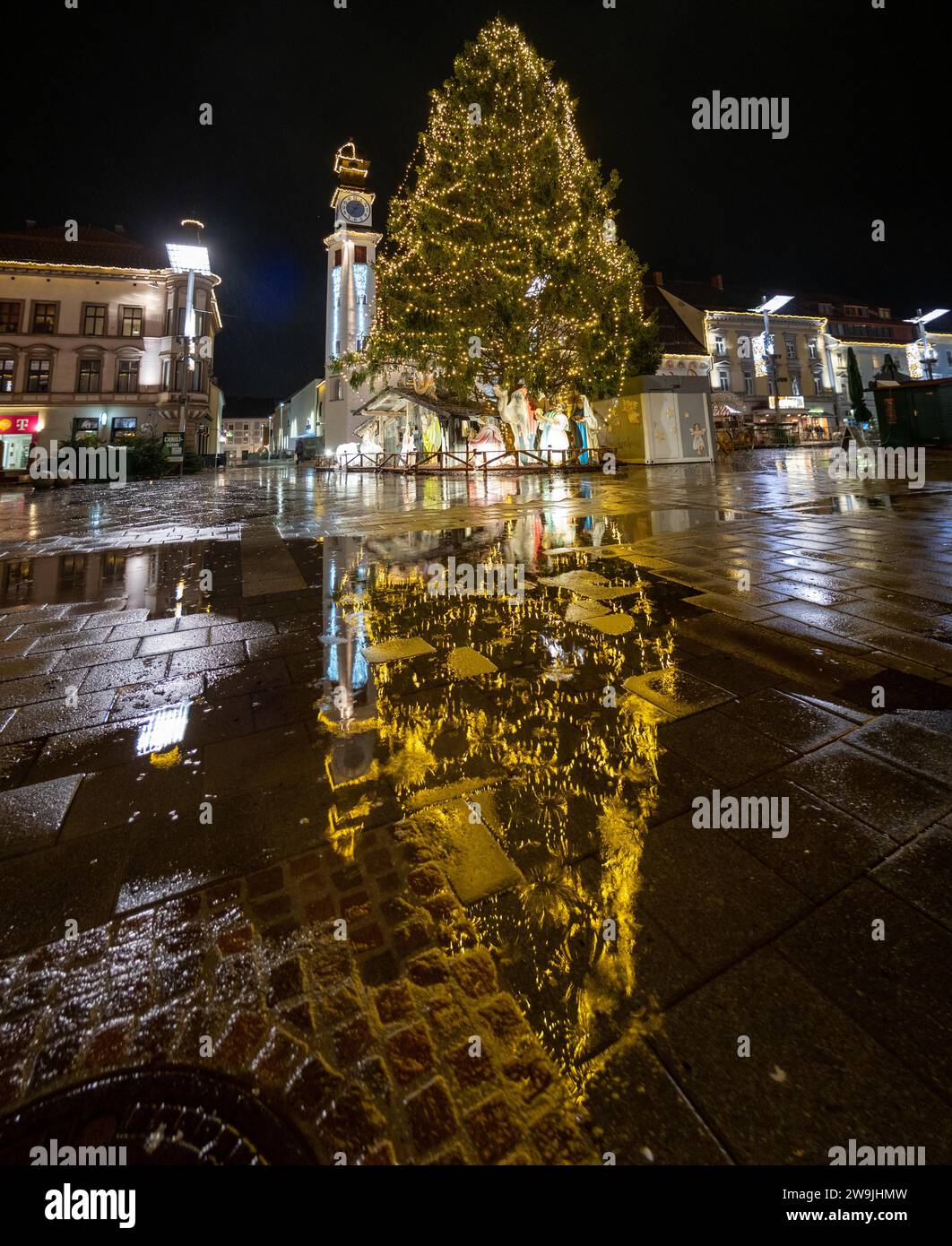 Árbol de Navidad iluminado, reflejo en el pavimento empapado de lluvia, Leoben, Estiria, Austria Foto de stock