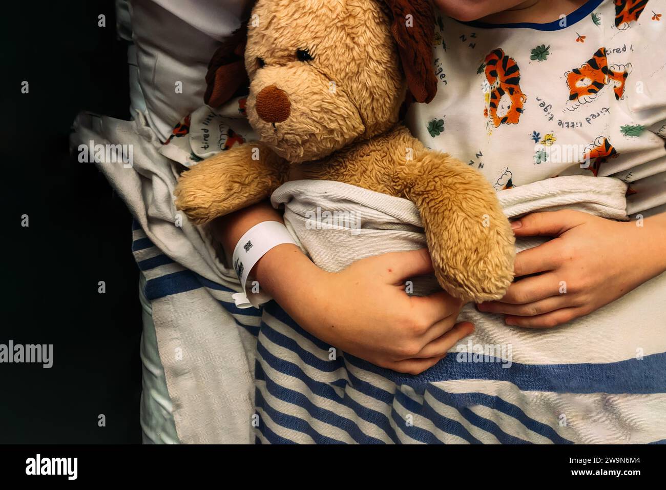 Niño acostado en cama de hospital sosteniendo animal de peluche Foto de stock