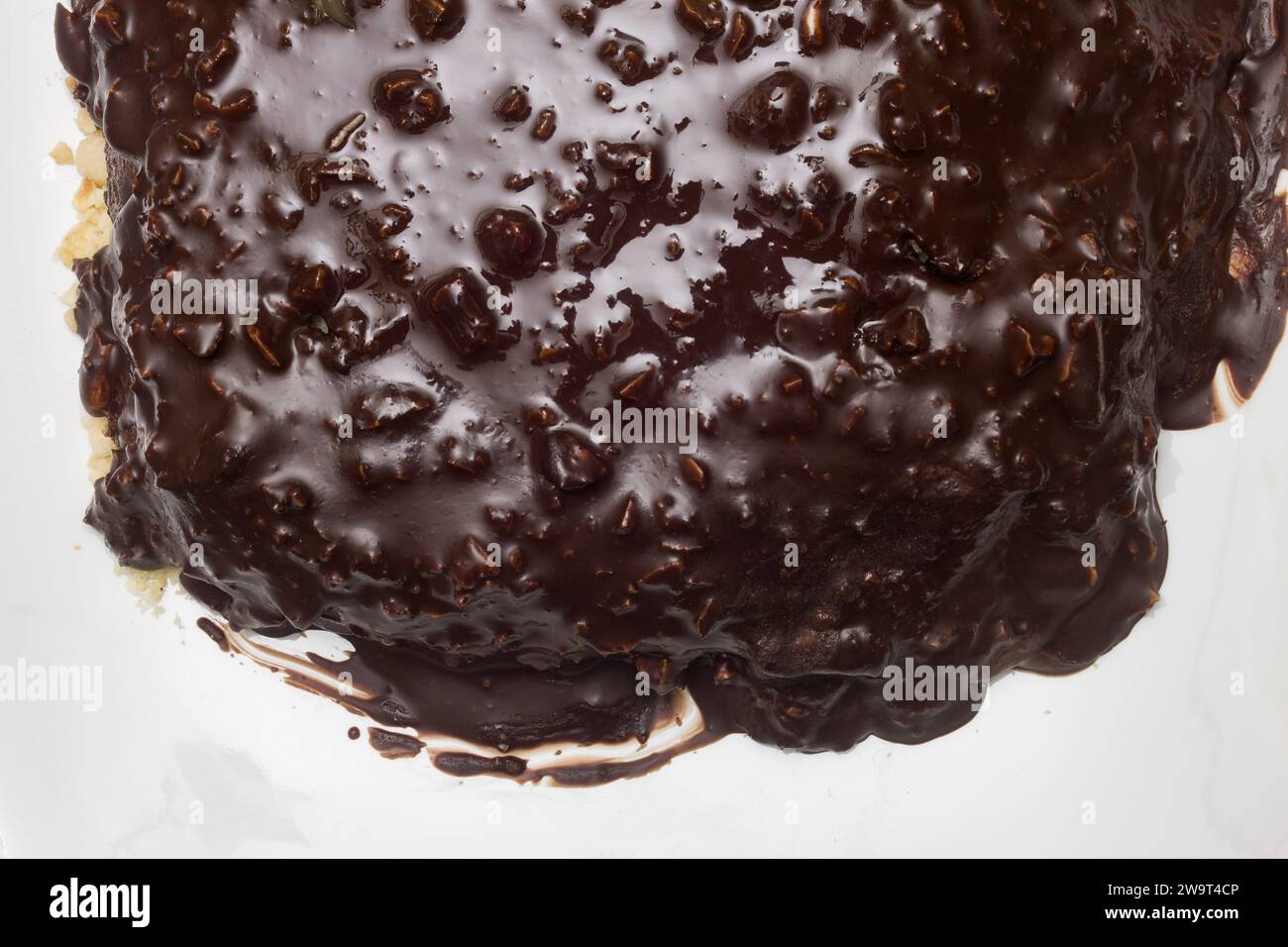 Vista superior de la capa superior de chocolate oscuro con almendras en el borde de un plato de cerámica blanca con espacio de copia. Foto de stock