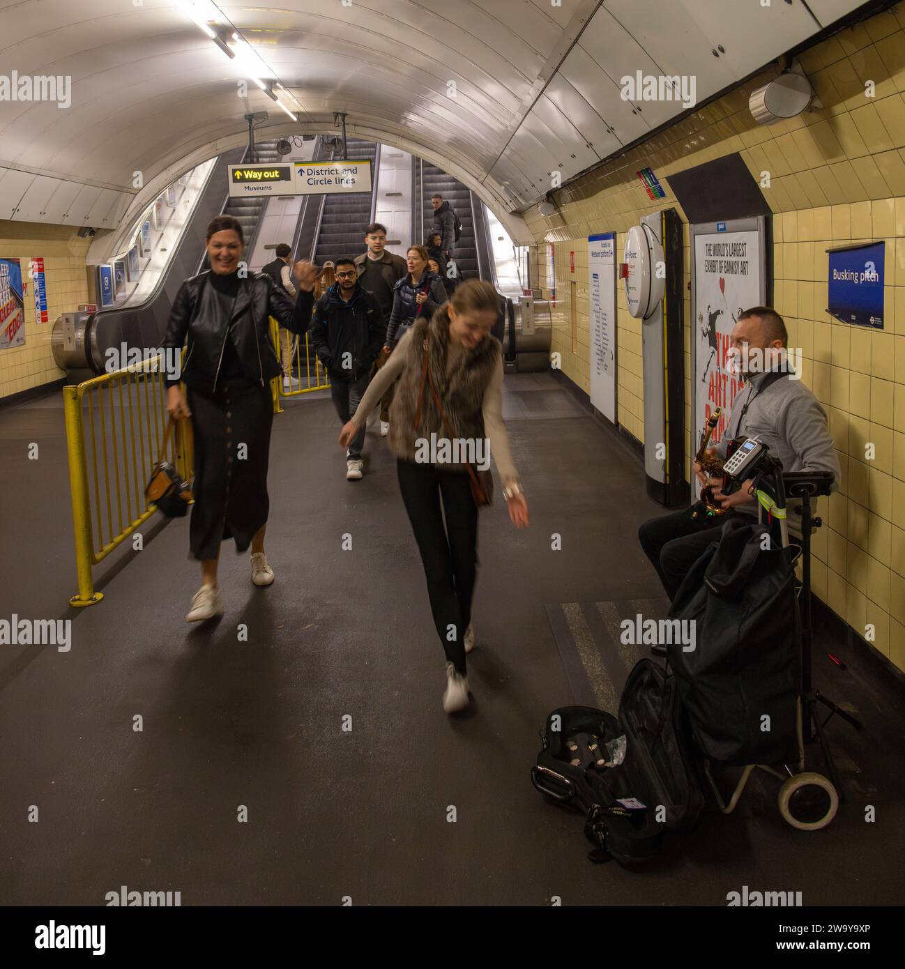 Chica dando dinero al saxofón jugando busker, London Underground, Reino Unido Foto de stock