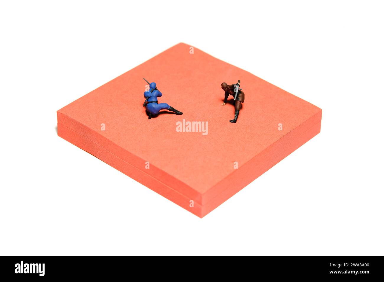 Fotografía creativa de figuras de juguete de personas en miniatura. Instalación de notas adhesivas. Dos ninja luchando en la arena de la esterilla roja. Foto de imagen Foto de stock