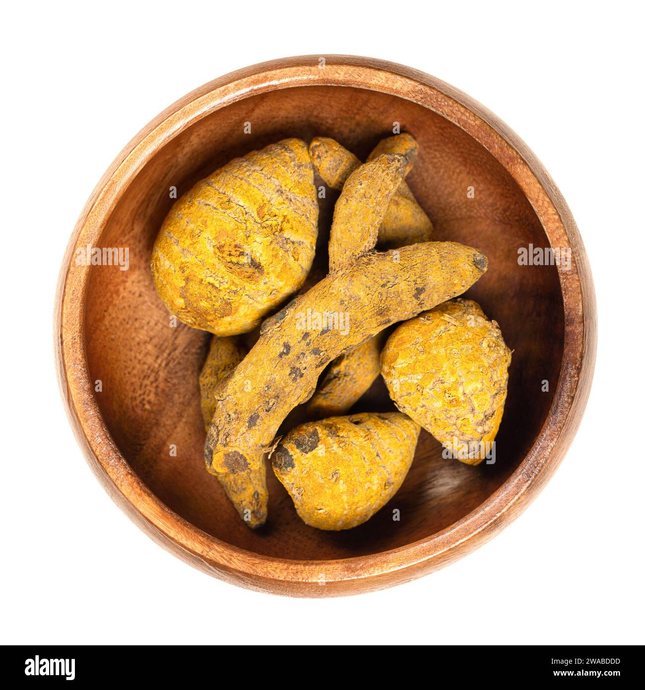 Seca la raíz entera de cúrcuma en un tazón de madera. Rizomas deshidratados de Curcuma longa, también llamados cúrcuma. Utilizado como especia y como agente colorante. Foto de stock