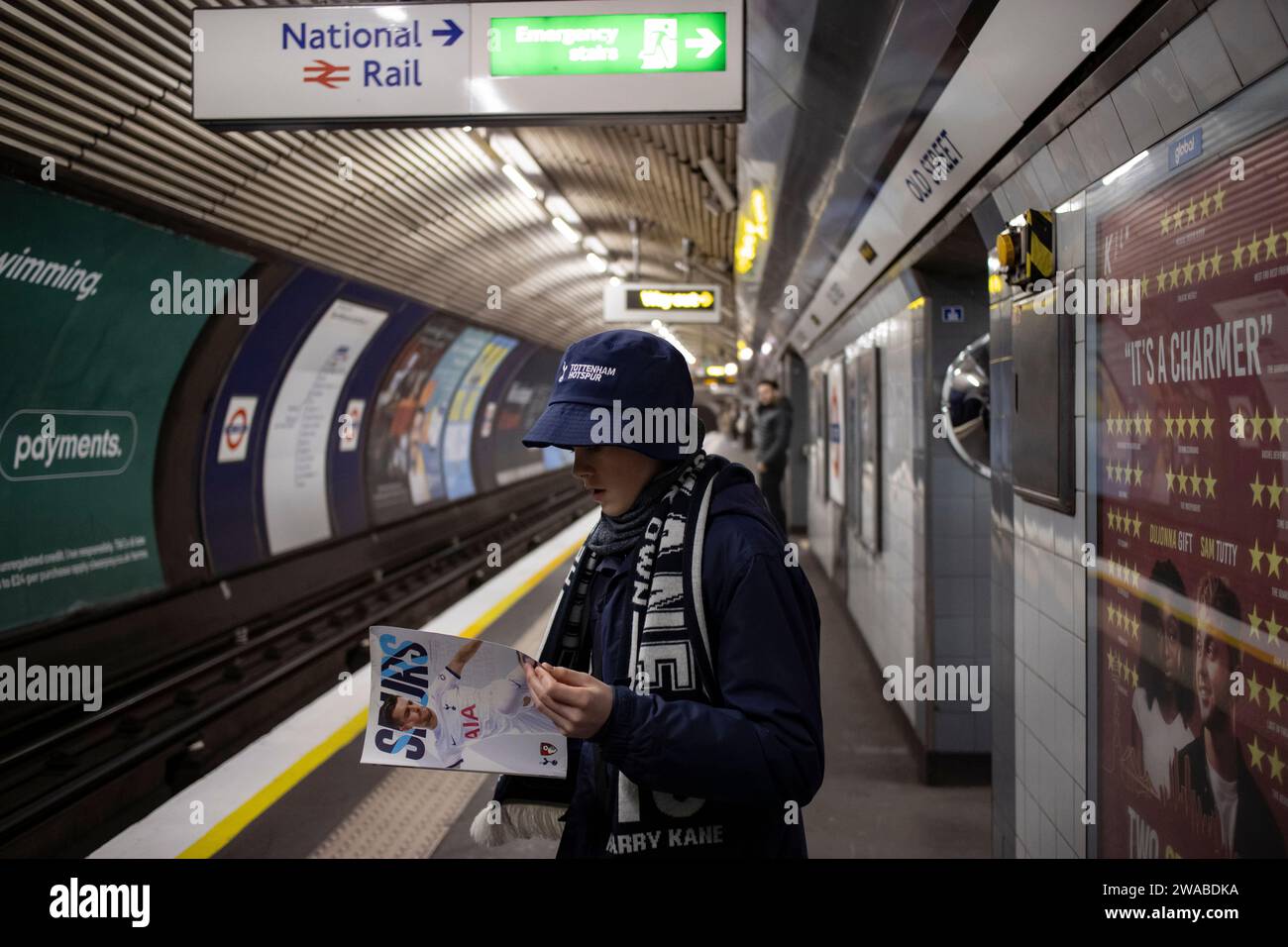 Joven aficionado al fútbol de los Spurs con su programa del día del partido viajando de vuelta a casa usando el metro de Londres, Inglaterra, Reino Unido Foto de stock