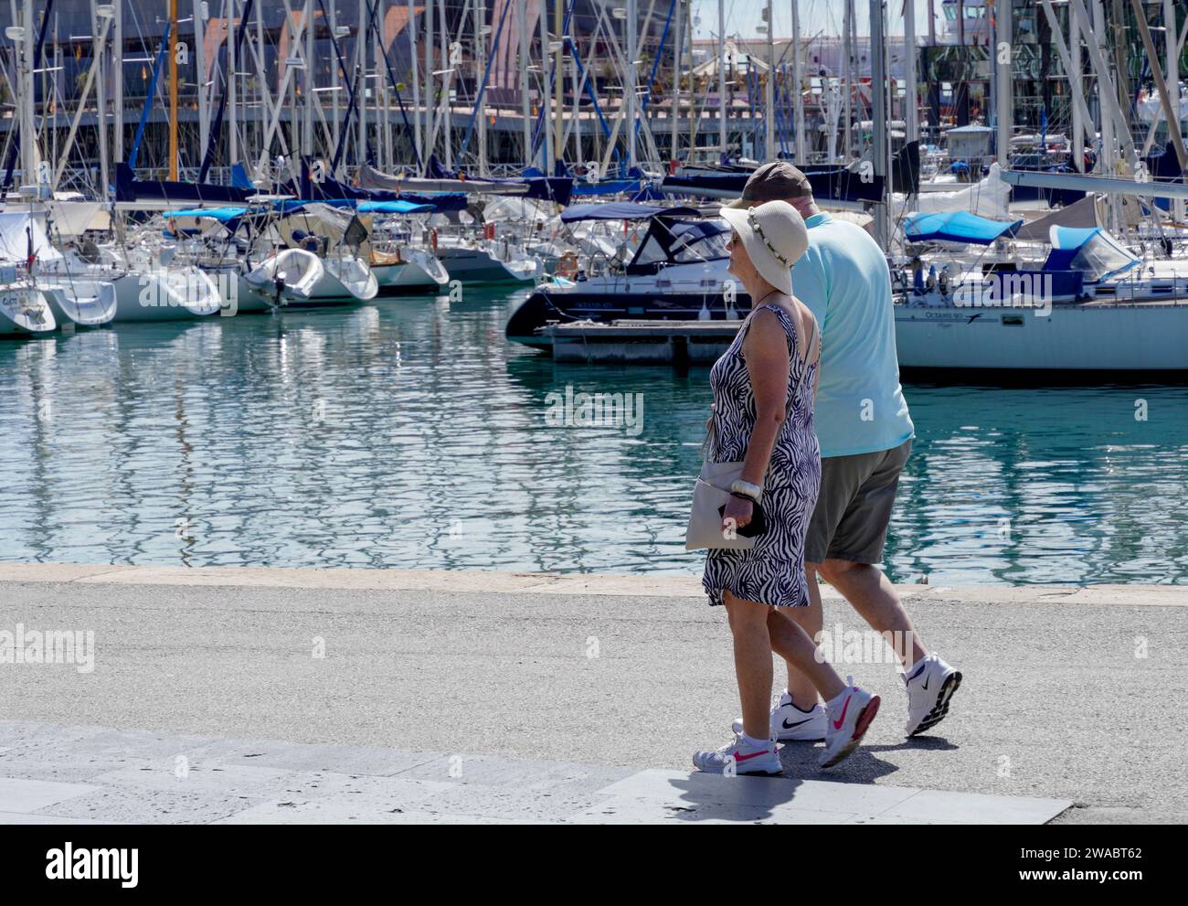 Barcelona, España - 26 de mayo de 2022: Una pareja mayor camina por el puerto deportivo con zapatos cómodos y deportivos de la misma marca, ambos tienen el mismo ritmo. Foto de stock