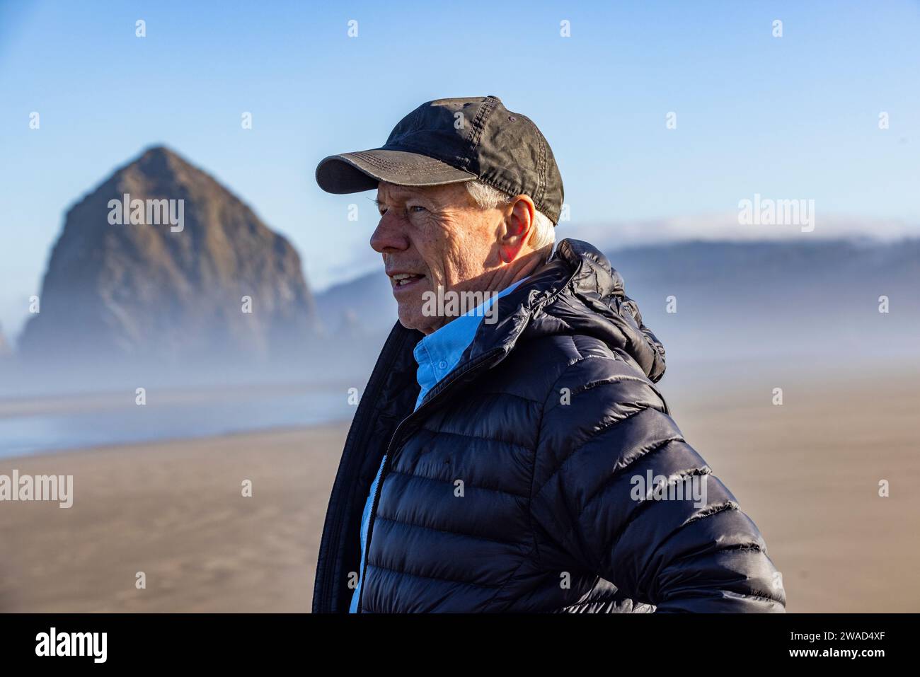 EE.UU., Oregon, Hombre de pie cerca de Haystack Rock en Cannon Beach en la niebla de la mañana Foto de stock