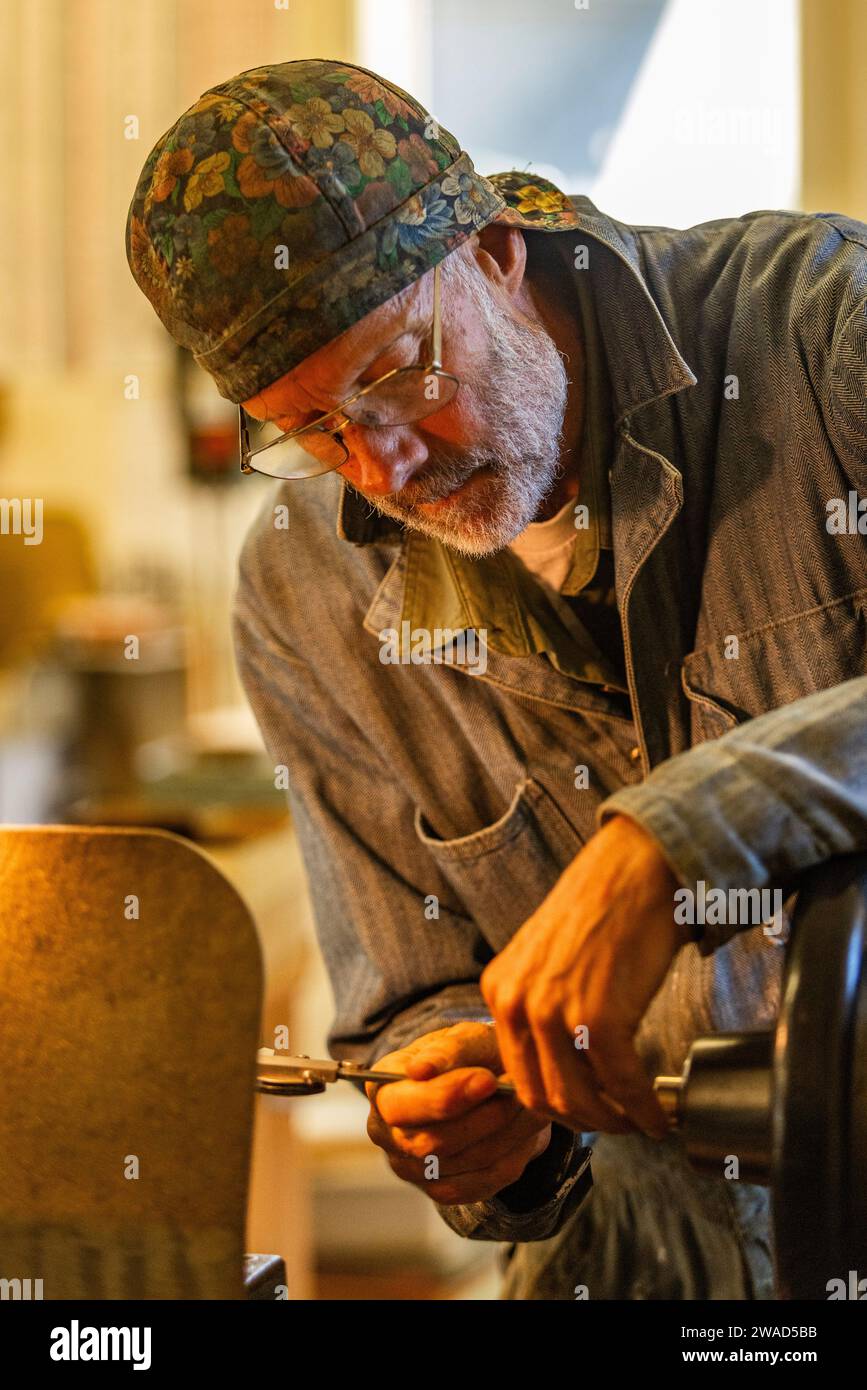 Artesano mayor de madera y metal artesano trabaja con herramientas eléctricas en taller Foto de stock