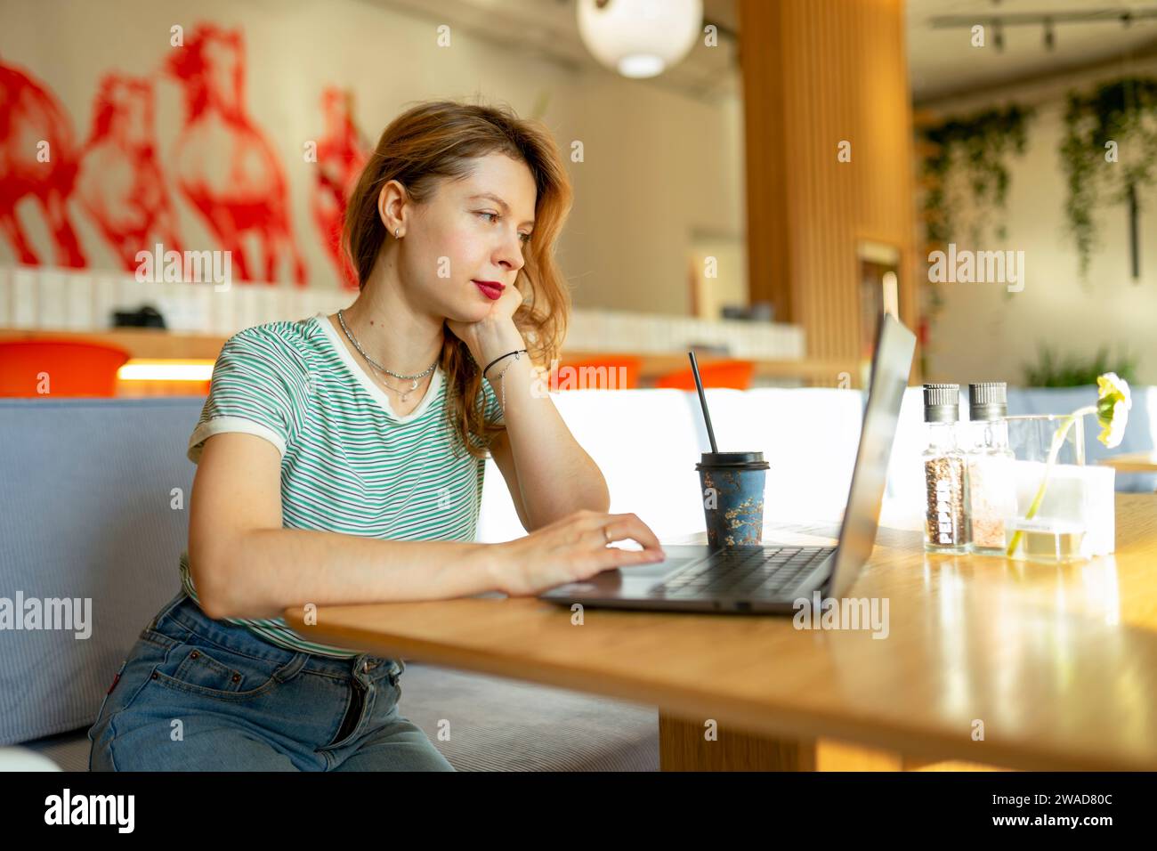 Mujer seria que trabaja en el ordenador portátil en café Foto de stock