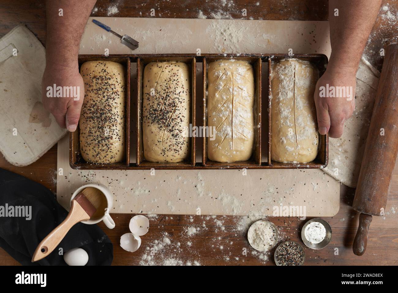 Directamente por encima de la vista de panadero preparando pan en la cocina Foto de stock