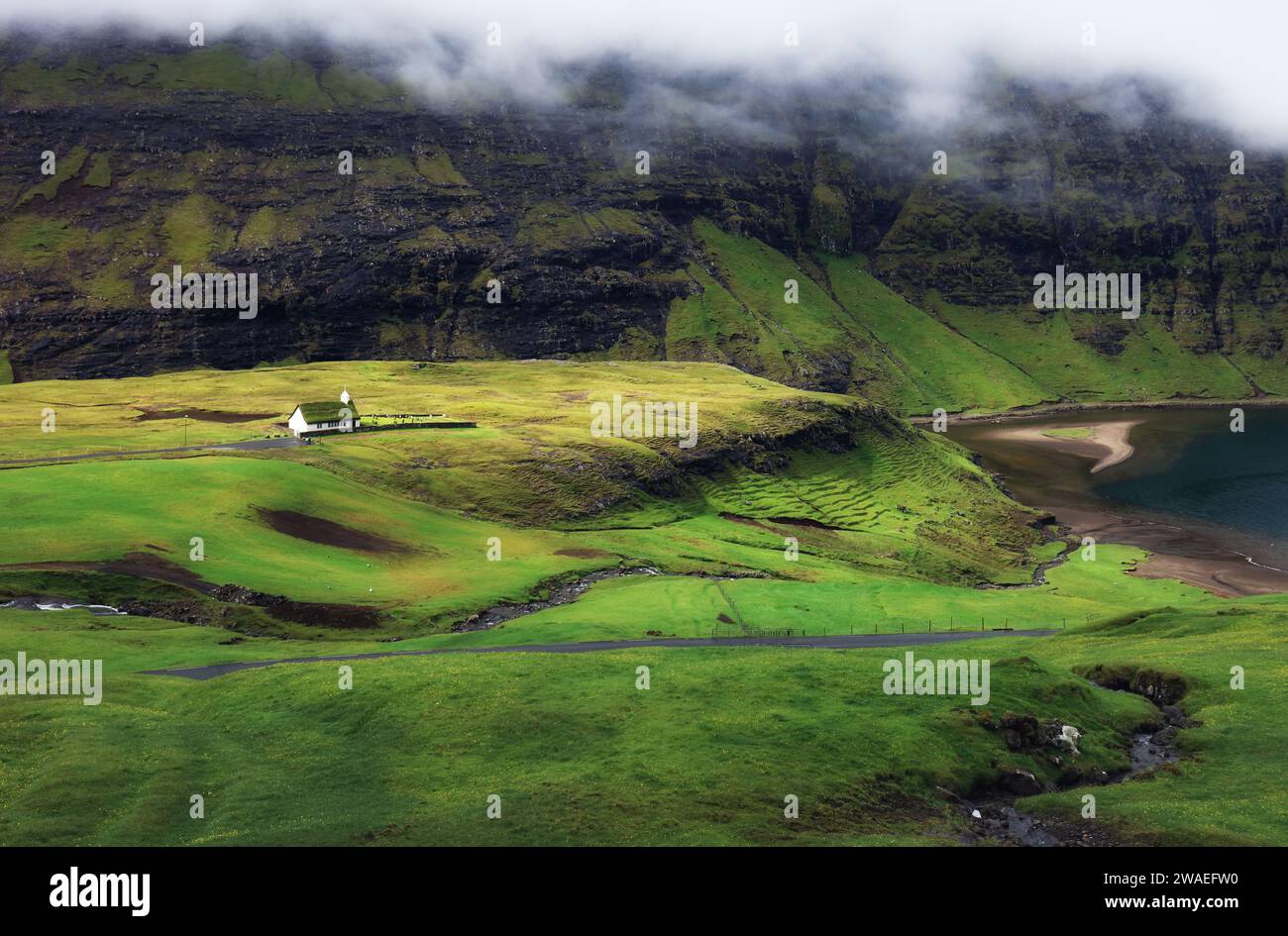 Verde paisaje de montaña con casas antiguas en las islas Feroe, Saksun Foto de stock