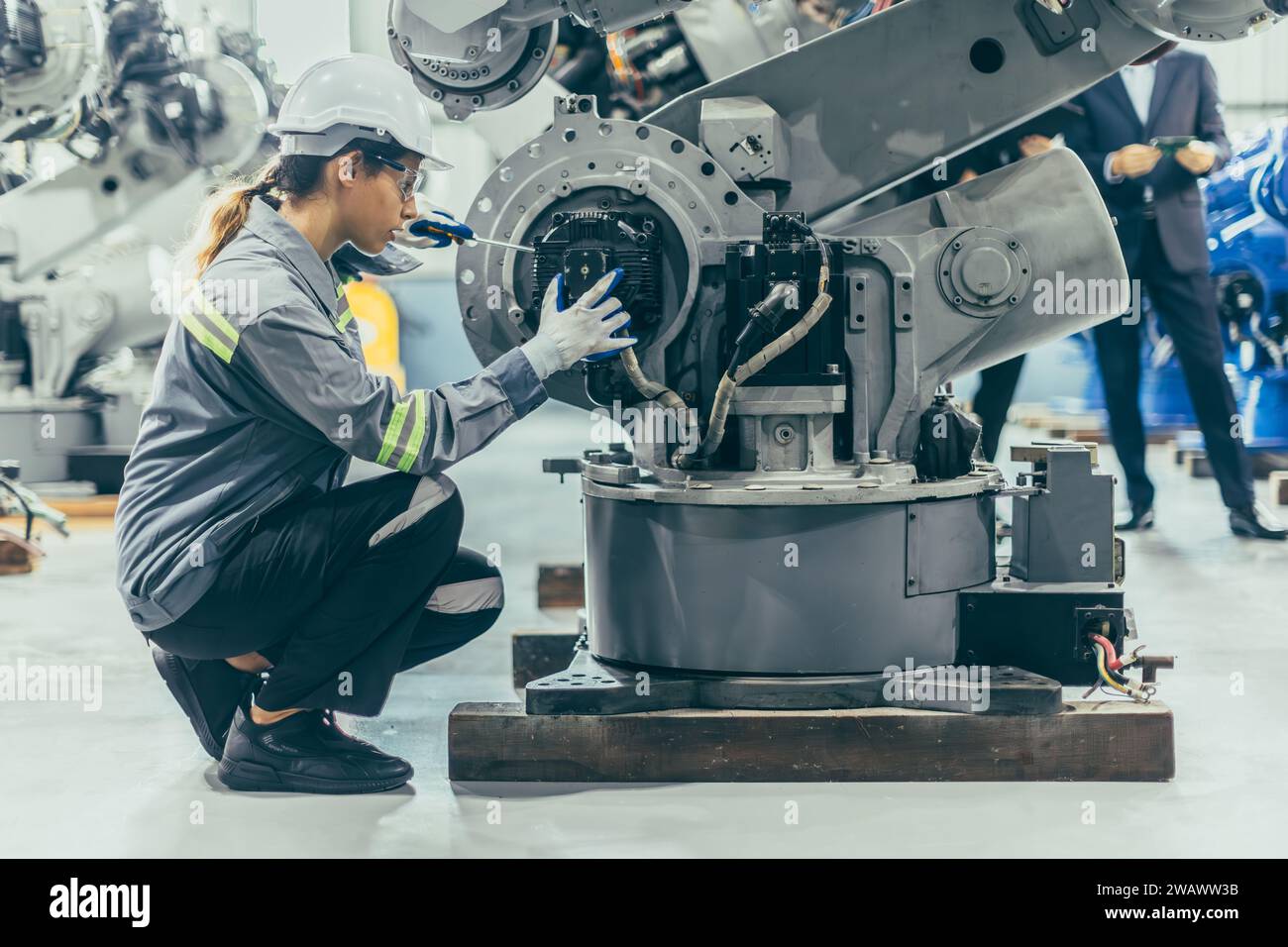 Ingeniero mecánico robótico mujer técnica que trabaja por adelantado en la industria robótica montaje de la planta de trabajo robot brazo reparación reparación mantenimiento o servicio grande m Foto de stock