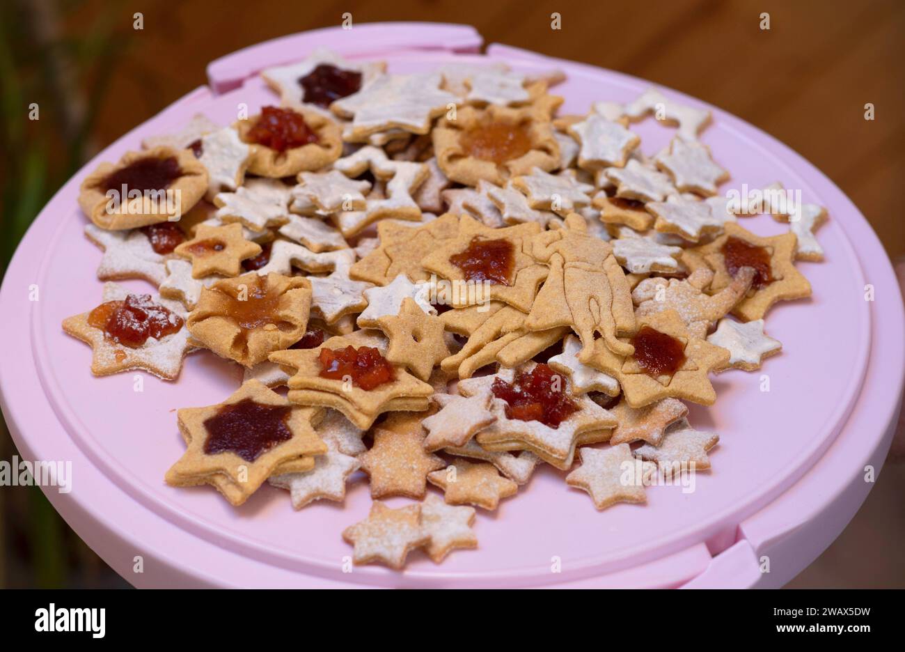 Pila de estrellas horneadas y superhéroe, galletas hechas a mano en un soporte rosa Foto de stock