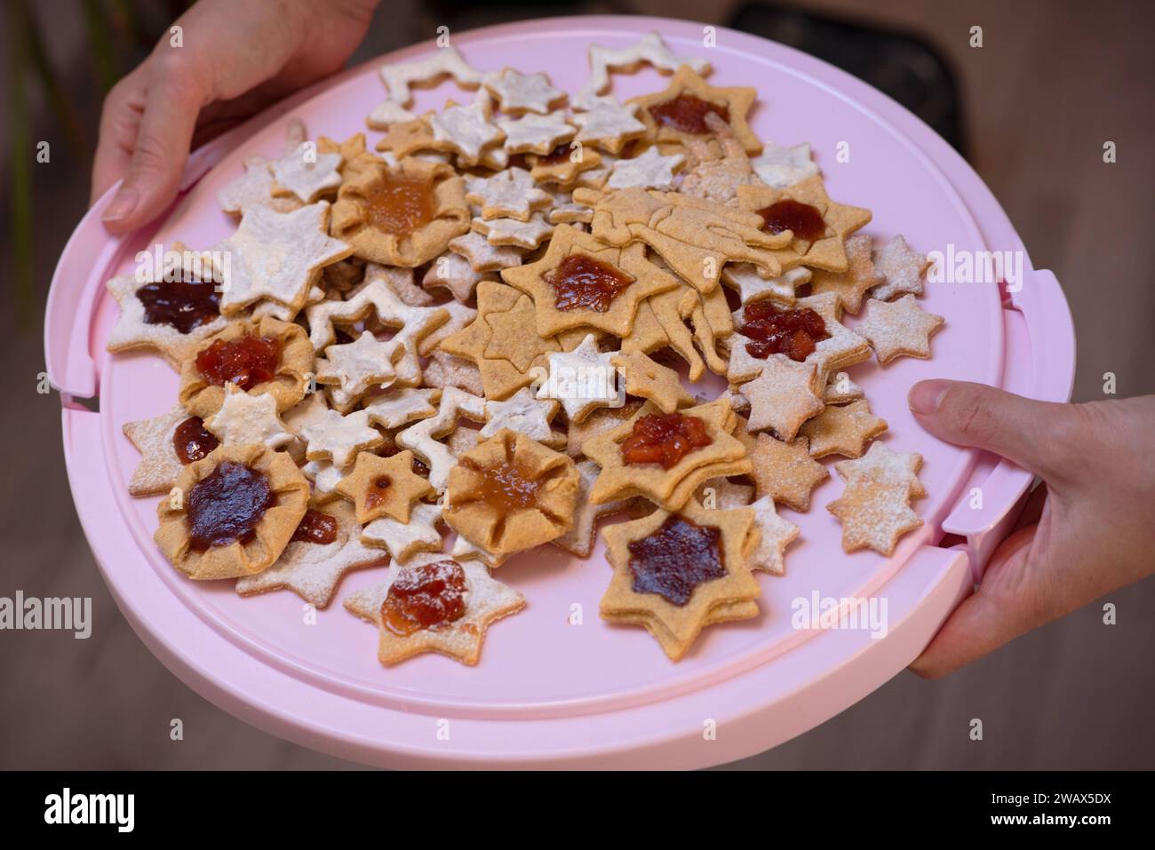 Mano sosteniendo una pila de estrellas horneadas y superhéroe, galletas hechas a mano Foto de stock