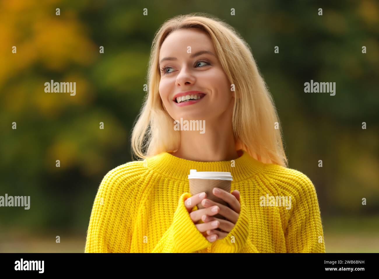 Vibraciones de otoño. Retrato de mujer feliz con taza de papel al aire libre Foto de stock