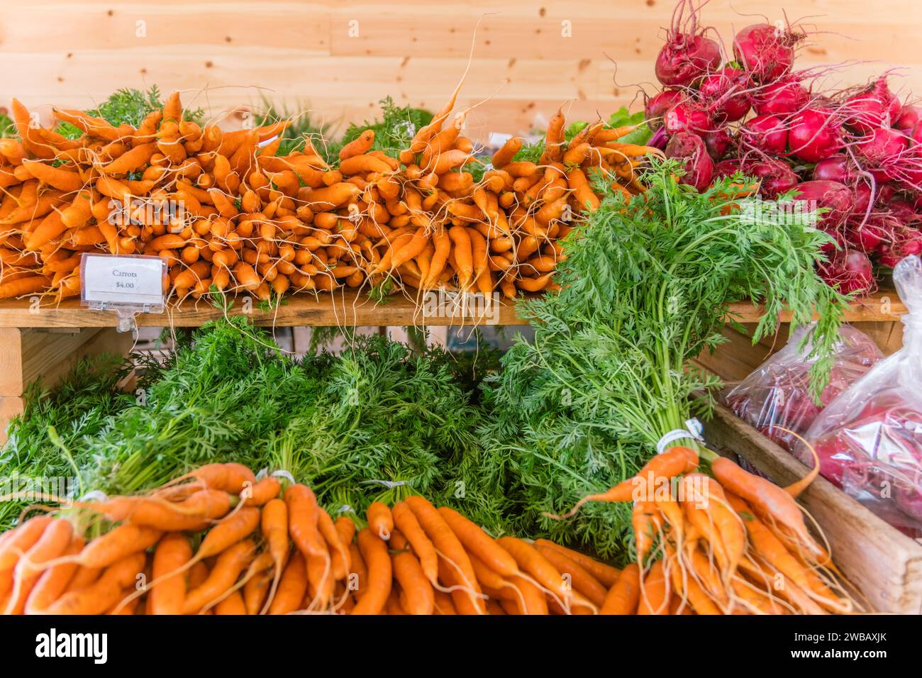 Primer plano de zanahorias y rábanos en exhibición en un mercado de agricultores al aire libre. Foto de stock