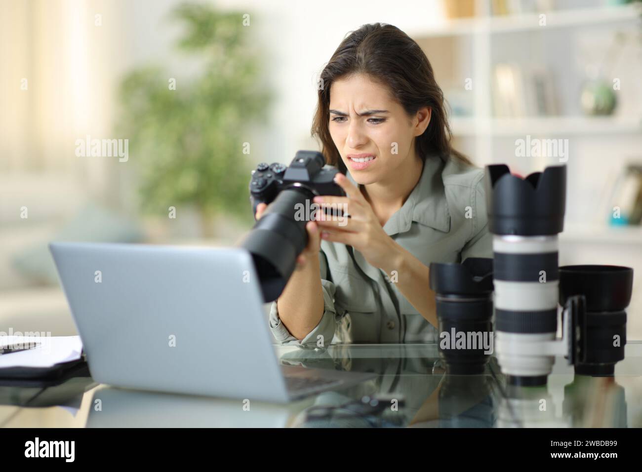 Fotógrafo molesto que comprueba la cámara después del trabajo en casa Foto de stock