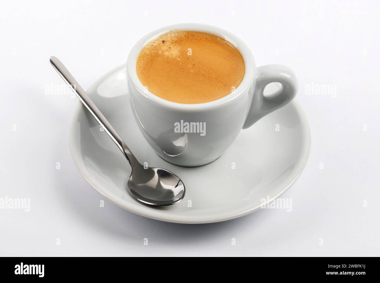 Taza de espresso con platillo y cuchara sobre fondo blanco Foto de stock