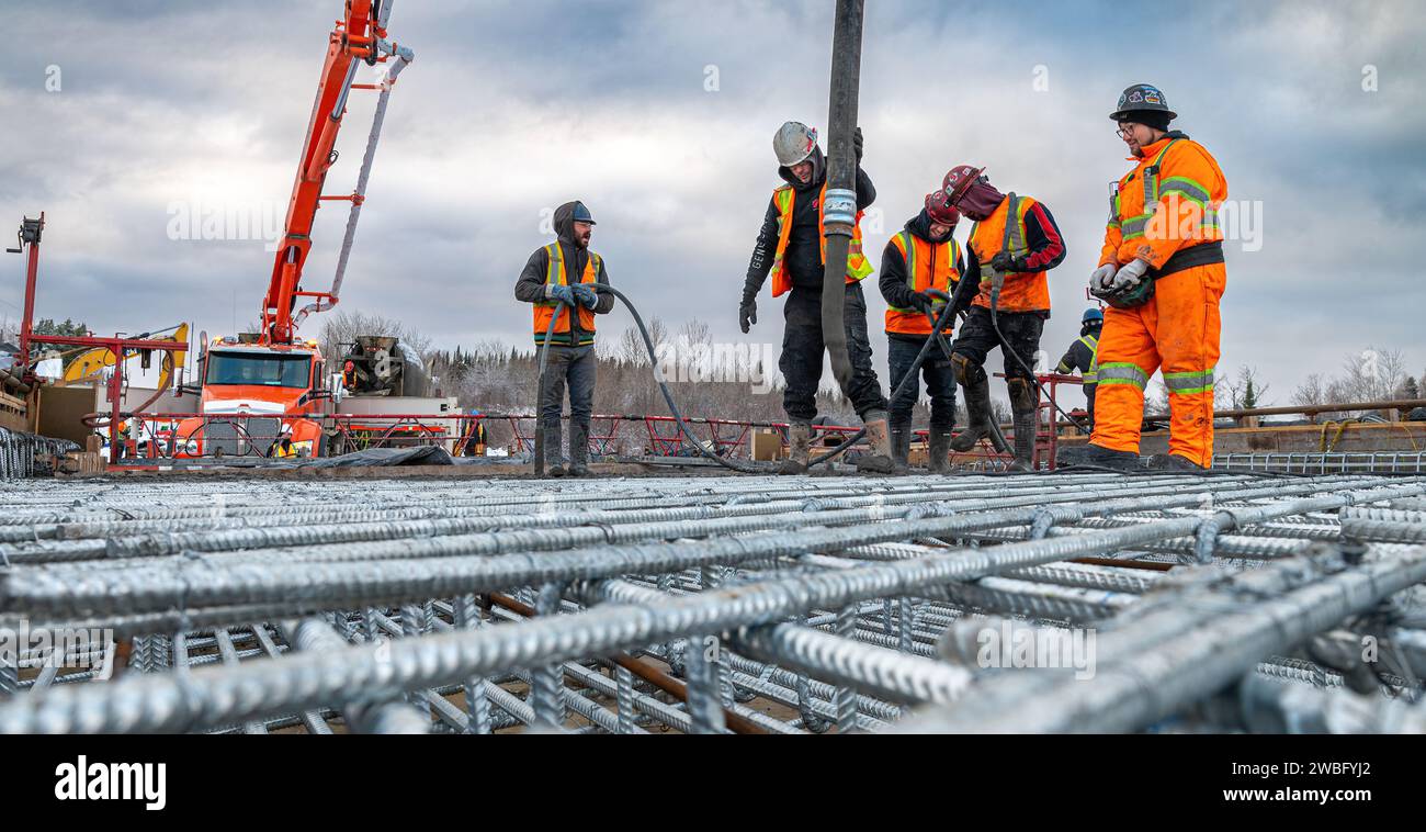 Rouyn-Noranda, Quebec, Canadá, 2022-11-25, trabajadores que construyen una losa de hormigón para un puente durante el invierno, utilizando una bomba de hormigón Foto de stock