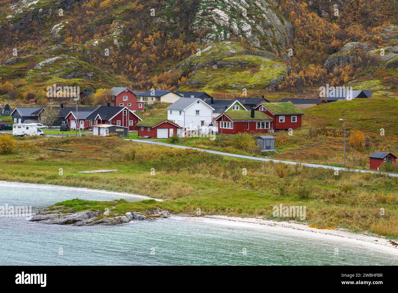 Casa roja con techo de hierba junto al océano, casas coloridas en la orilla del Atlántico Norte. Casa de vacaciones de madera en las islas de Hillesøy Foto de stock