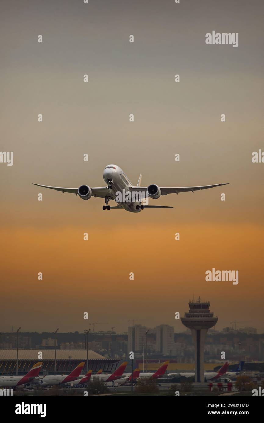 Hermosa imagen de un avión de pasajeros despegando del aeropuerto con los últimos rayos de sol reflejados en las nubes Foto de stock