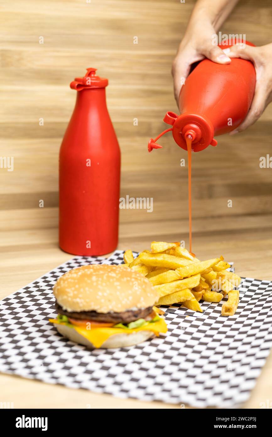 poner ketchup en papas fritas, ketchup, deliciosa hamburguesa. Comida rápida y apetitosa, restaurante estudio foto Foto de stock