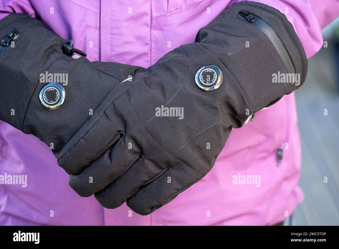 Una mujer con guantes calentados por batería durante el clima frío. Los guantes tienen ajustes de calor variables y ayudan a aquellos que sufren de la enfermedad de Reynauds Foto de stock